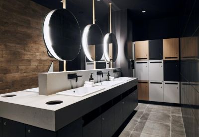 Modern locker room and vanity area with backlit circular mirrors.