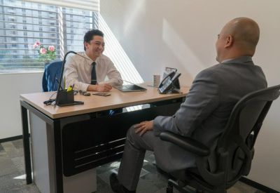 Private glass-walled office with a wooden desk and city views.