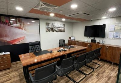 Modern meeting room with a large ship mural, wooden table, and black chairs.