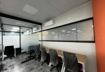 Individual workstation behind a glass wall with a light-wood desk.