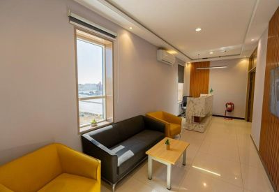 Sunlit waiting area featuring a black sofa, yellow armchair, and a small coffee table.