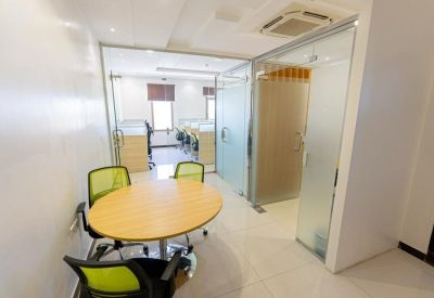Bright glass-enclosed meeting room with a round wooden table and lime green chairs.