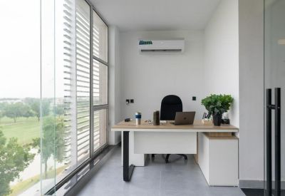Private glass-walled office with natural light and a view of greenery.