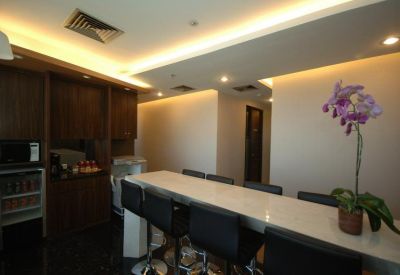 Sleek communal kitchen area with a high breakfast bar, stools, and a potted orchid.