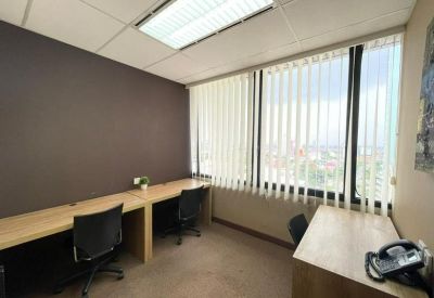 Private office suite with wood-finish desks and vertical window blinds.