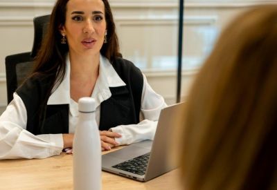 Close-up of a professional woman in a meeting room with a laptop and water bottle.