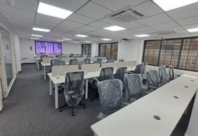 Wide-angle view of a bright office featuring several rows of modern workstations.