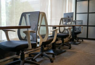 Row of modern mesh office chairs and sleek workstations by a window.