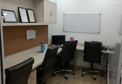 Workstation area with a long desk, several ergonomic chairs, and a whiteboard on the back wall.