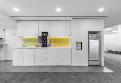 Clean communal kitchen area with white cabinetry and a coffee machine.
