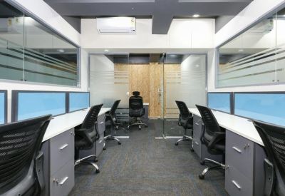Symmetrical coworking area featuring rows of desks with blue privacy screens and grey cabinetry.