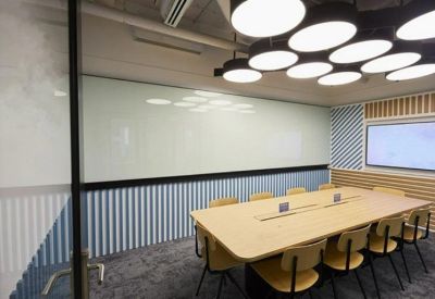 Modern meeting room with a large wooden table and circular pendant lighting.