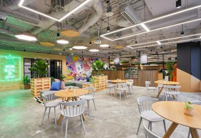 Spacious coworking area with round wooden tables and indoor plants.