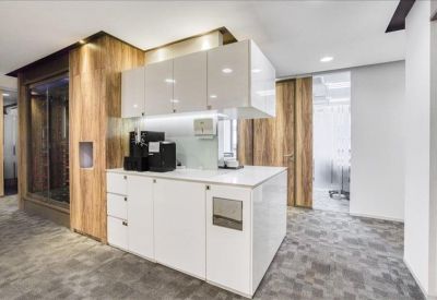 Communal kitchen area with white cabinetry and wood-paneled walls.