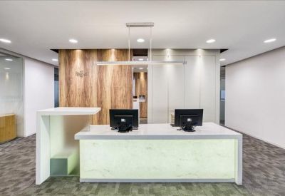 Bright reception desk with two monitors set against a wood and glass backdrop.