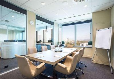 Professional meeting room with a light wood table, tan chairs, and a whiteboard.