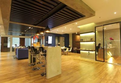 Spacious breakout area with a high-top bar table, wooden floors, and glass-enclosed meeting spaces.