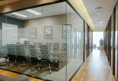 A modern glass-walled boardroom with patterned frosted privacy film and ergonomic chairs.