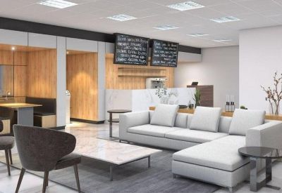 Spacious communal lounge area with a white L-shaped sofa and a coffee bar in the background.