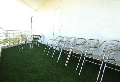 Outdoor communal terrace with metal seating on artificial turf.