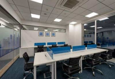 Modern open-plan workspace featuring rows of desks with blue privacy dividers.