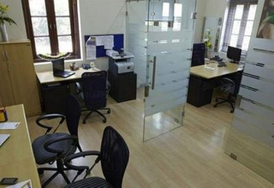 Shared office suite with multiple workstations and frosted glass partitions.