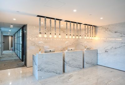 Modern marble reception area with three minimalist desks and designer pendant lighting.