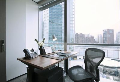 Private office suite with a wooden desk and ergonomic chair overlooking the city skyline.
