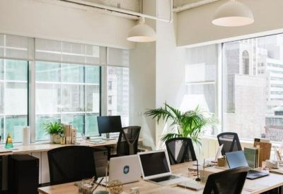 Bright open-plan office space with rows of desks and large windows overlooking the city.