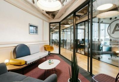 Stylish meeting lounge with glass partitions, comfortable seating, and a red area rug.