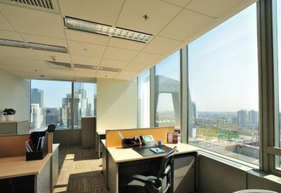 Bright corner office with wooden desks and large windows offering panoramic city views.
