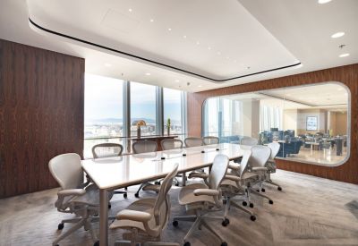 Large professional boardroom with a long white table and ergonomic grey chairs.