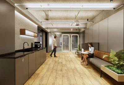 Spacious communal breakout area with a modern kitchen, wooden flooring, and comfortable seating with indoor plants.