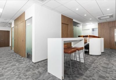 High-top white communal table with leather bar stools set against wooden wall panels.
