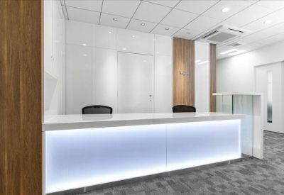 Bright white reception desk with integrated blue LED under-lighting and wooden wall accents.