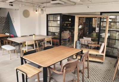 Open-plan office area with wooden desks, grey chairs, and a unique mobile timber workstation booth.