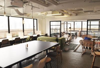 Spacious coworking area featuring a large black communal table and peripheral window seating.