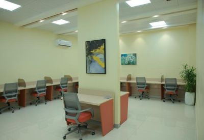 Coworking area featuring a central wooden desk and indoor greenery.