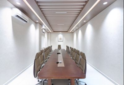 Formal boardroom with a long wooden table and modern pendant lighting.