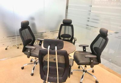Small breakout table surrounded by four black mesh chairs for informal meetings.