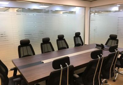 Spacious boardroom with a large dark wood table and black ergonomic mesh chairs.