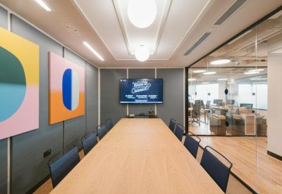 Long wooden boardroom table in a meeting room with colorful abstract wall art.