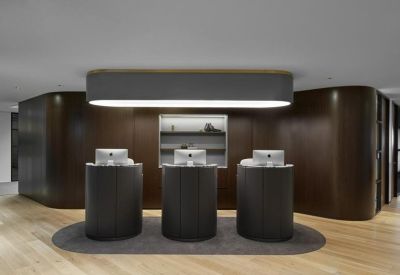 Sleek reception area with three dark minimalist desks and a large overhead light.