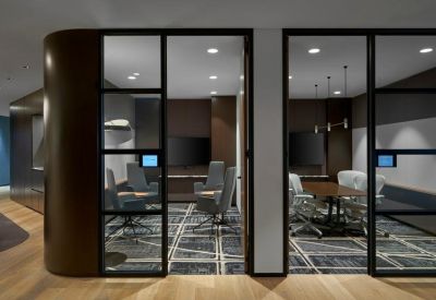 View into two private glass-walled meeting rooms with dark wood accents.