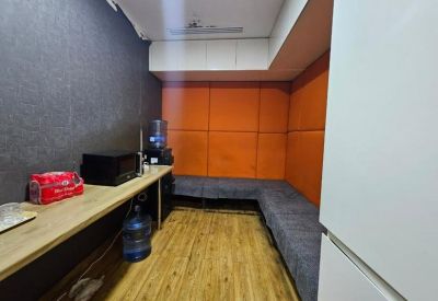 Vibrant breakroom area with orange padded wall panels and a grey corner bench seating area.