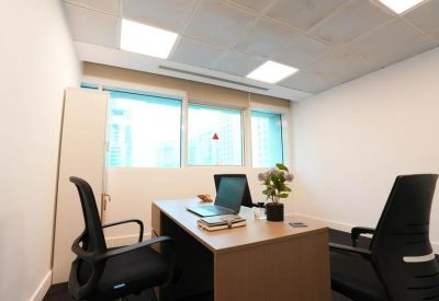 Office space with two black swivel chairs and window light.