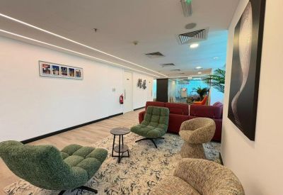 Communal lounge area with green armchairs and a red sofa on a patterned rug.