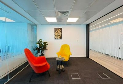 Meeting nook with colorful chairs, a small table, and a glass wall divider.