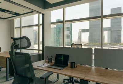 Shared office space with workstations facing large windows and city views.