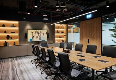 Professional boardroom with a long wooden table, black leather chairs, and accent lighting.